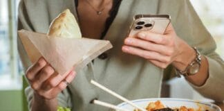 5 rodzajów bułek bao, które uratują każdy zabiegany dzień w pracy Osoba je bao w azjatyckiej restauracji, przeglądając telefon