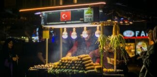 Nocne tureckie stoisko uliczne z grillowaną kukurydzą i tłumem ludzi