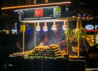 Nocne tureckie stoisko uliczne z grillowaną kukurydzą i tłumem ludzi