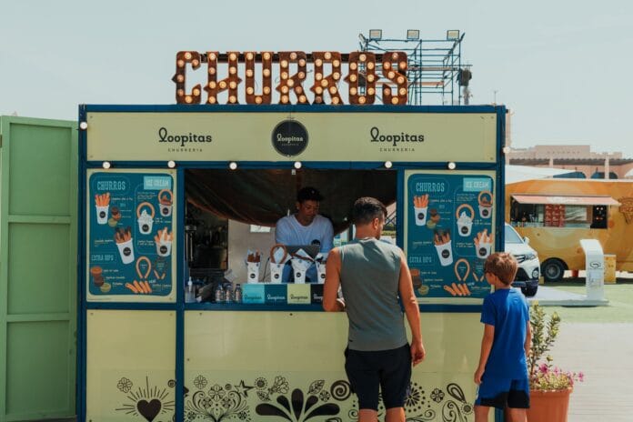 Ojciec i syn zamawiają churros na targowym stoisku w Dubaju Ojciec i syn zamawiają churros na targowym stoisku w Dubaju