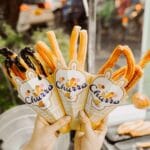 Zbliżenie na churros w papierowych rożkach trzymanych na zewnątrz