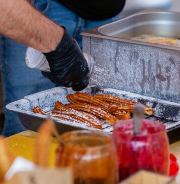 Ciepłe dania w ruchu na chłodne dni: od koreańskich placków po tureckie gözleme Zbliżenie na ulicznego sprzedawcę przygotowującego churros z dodatkami